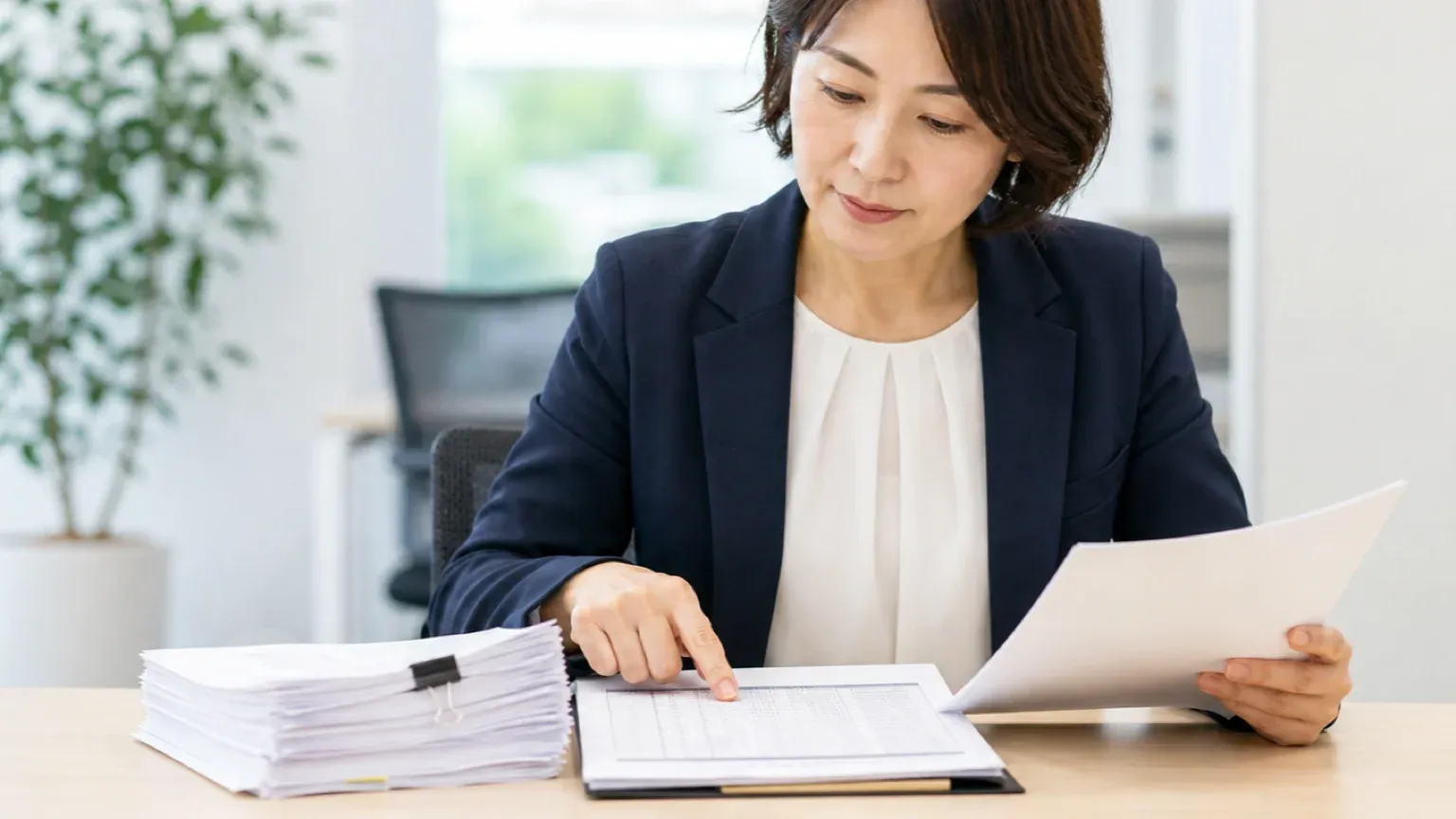 手元の帳票とデータ一覧を照らし合わせて確認する担当者の手元