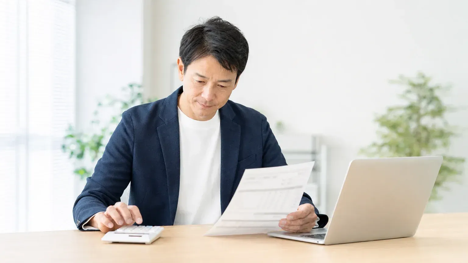 受託開発の見積書を電卓で確認しながら金額の妥当性を検討する発注担当者