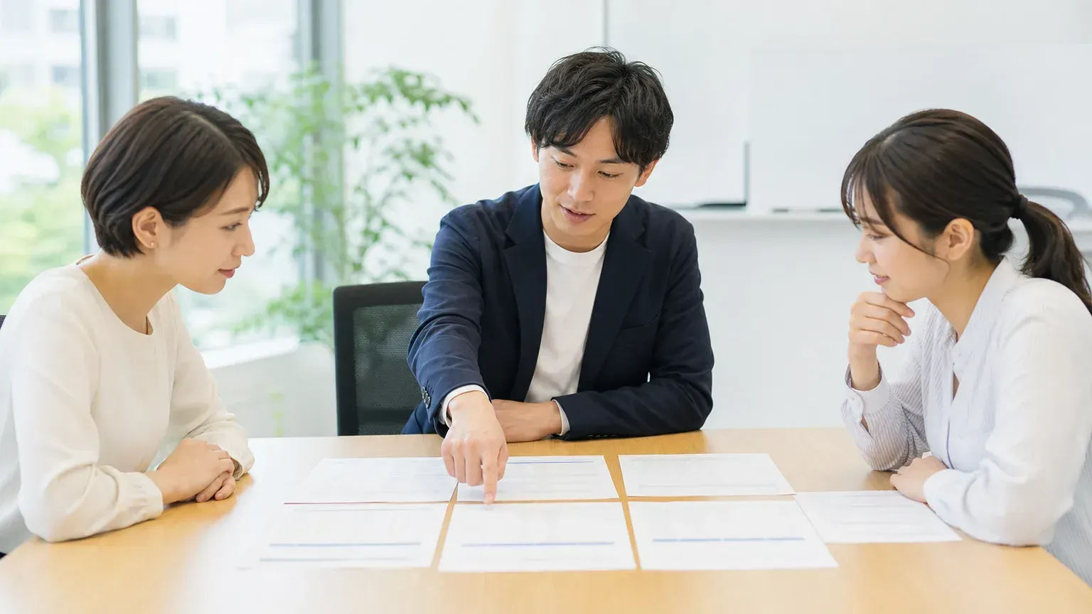 複数の担当者が回答依頼シートを見比べながら移行パートナーの実績を確認している打ち合わせの様子
