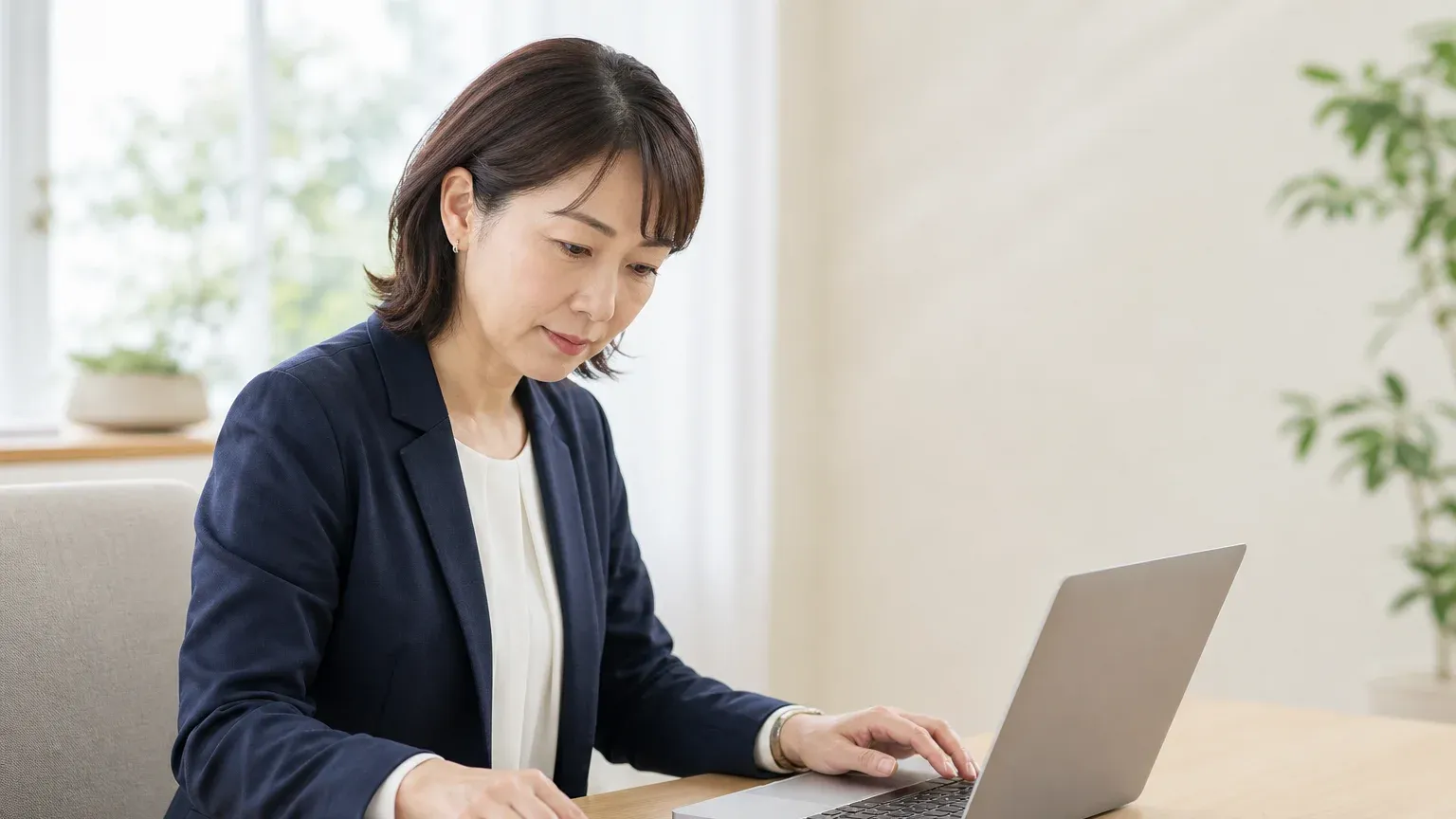ノートPCで稟議用の資料に保守費の推移と手作業時間の数字をまとめている担当者