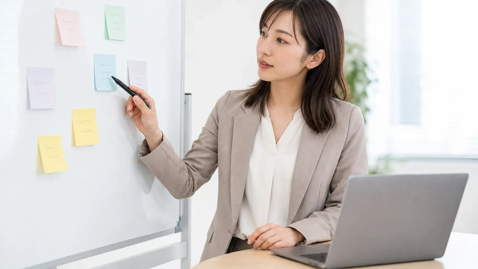 ホワイトボードに貼った付箋を指しながら基幹システム入れ替えのリスクを整理する30代女性の情シス担当者