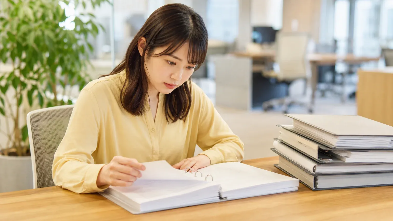 社内マニュアルの束を前に生成AIへ何を覚えさせるかを検討するDX推進担当者