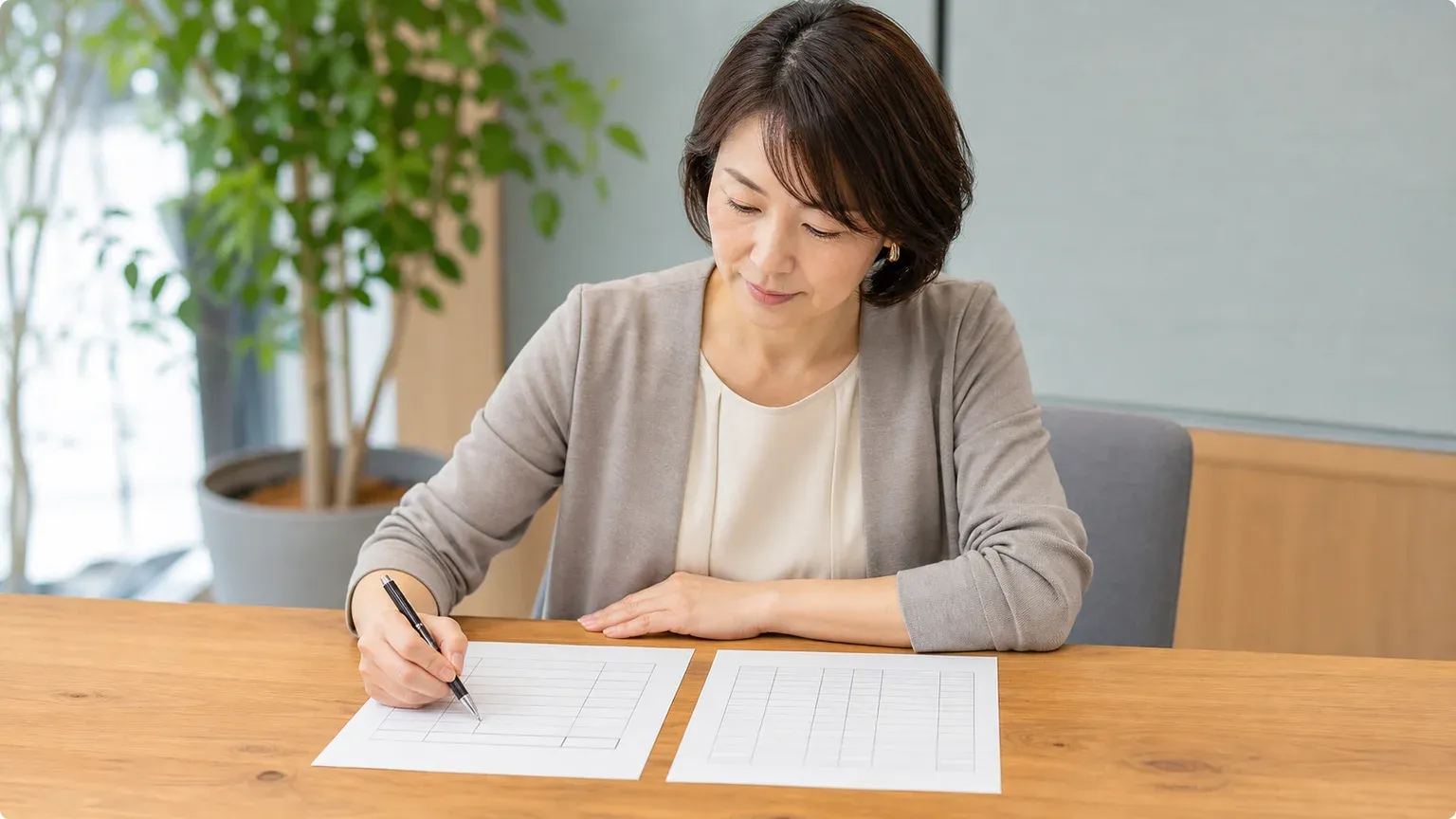 明るいオフィスのテーブルで40代女性の担当者が点検の指摘事項の書類とシステム一覧を並べ、ペンで印を付けながら優先順位を整理している場面
