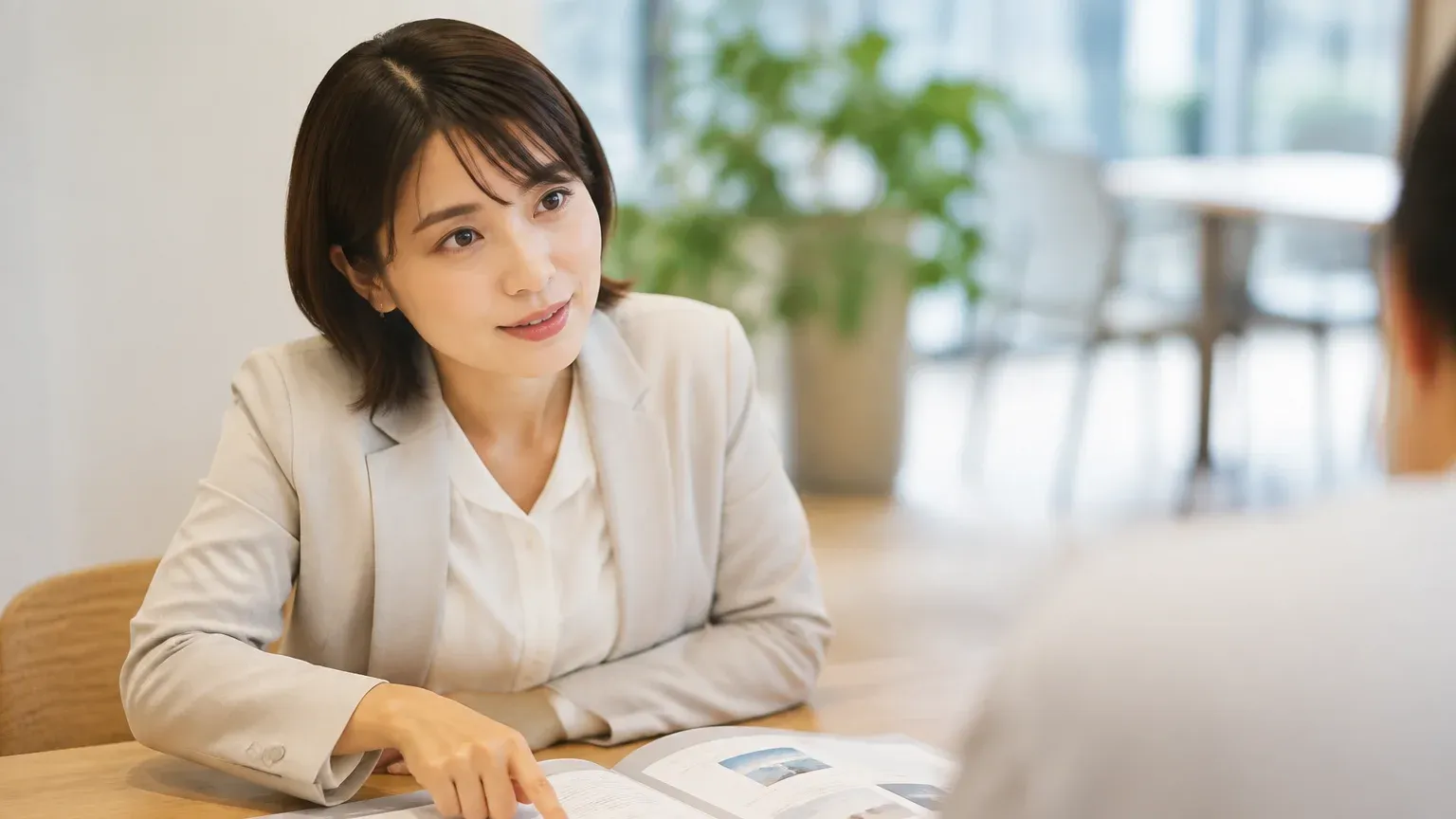 打ち合わせのテーブルで提案書に指を置き、担当者が説明を聞きながら内訳を確かめている場面