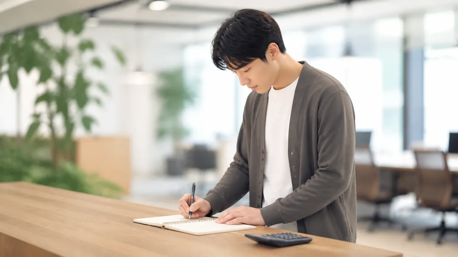 カウンターで立ったままノートに作業時間と件数を書き出している担当者