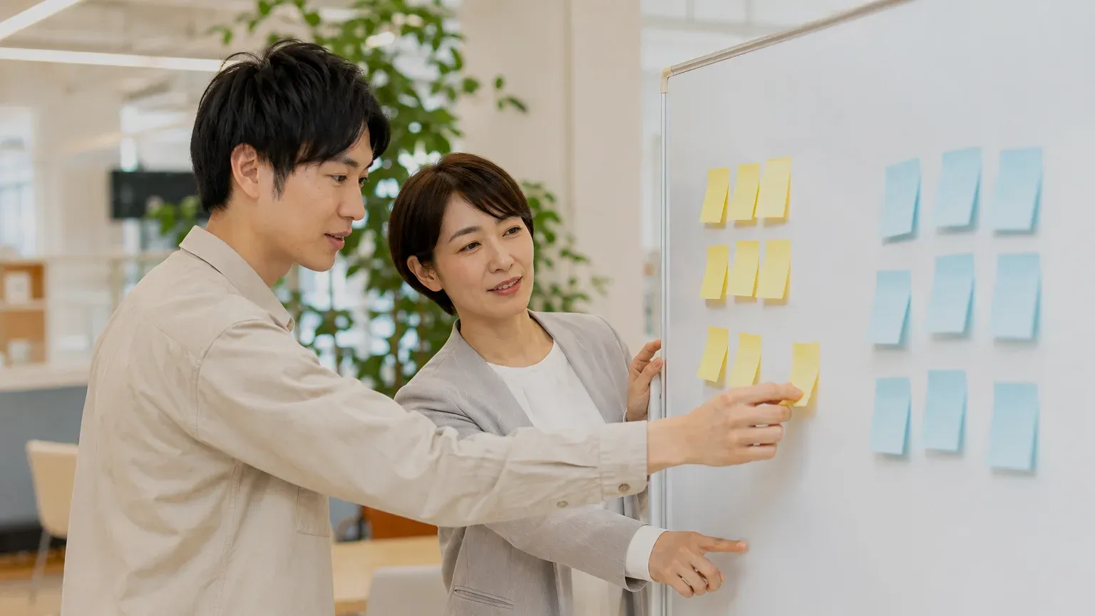 ホワイトボードに貼った付箋を使って、担当者二人が移行する範囲と捨てる範囲を仕分けている場面