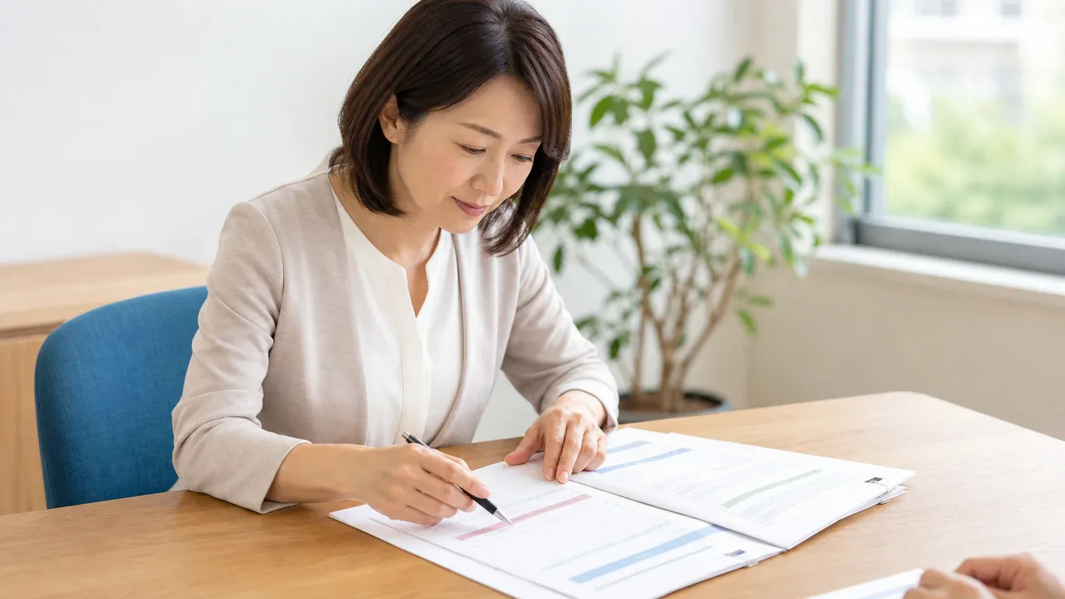 明るい会議室で、担当者が見積書と契約書の綴じ資料を開き、保守運用の欄をペンで指して確認している場面
