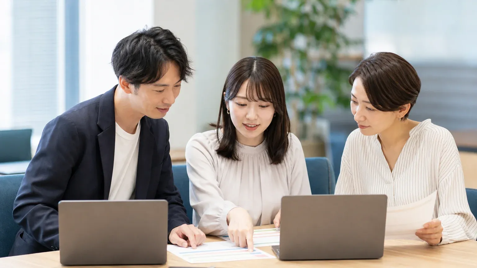 会議室に集まった現場の担当者3名が、手元の資料とノートPCで受け入れテストのシナリオを試している場面